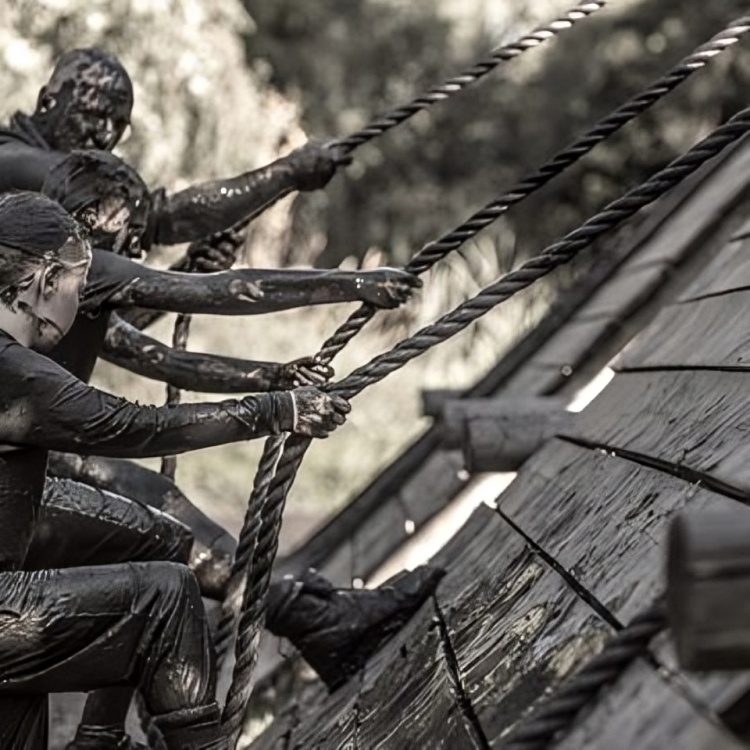 Participants climbing a muddy obstacle course